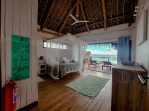 a bedroom with a bed and a balcony with the ocean at The Beach House in Inhambane