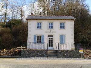 Casa blanca con ventanas azules y pared de piedra. en La Fourmondière supérieure, maison éclusière en Montflours