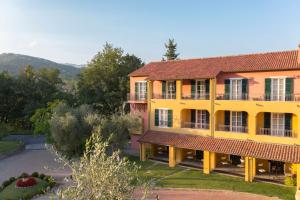 un gran edificio amarillo con techo rojo en La Meridiana Hotel & Golf Resort, en Garlenda