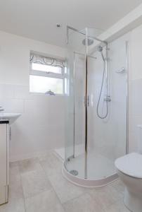 a white bathroom with a shower and a toilet at Beach Retreat - Mount Brioni in Downderry