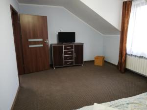 a bedroom with a bed and a tv and a door at Villa Dobry Adres in Dziemiany