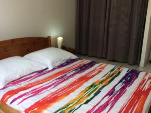 a bed with a colorful blanket on it with a candle at Appartement lumineux à Les Trois-Îlets - 70 m² - Vue sur mer in Les Trois-Îlets