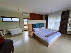 a bedroom with a large bed and a bath tub at No 16 Elements - 5 Bedroom Beauty in Moheme +49 photos