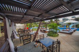 an outdoor patio with tables and chairs and a pool at Aimberê Eco Resort Hotel in Coqueiro