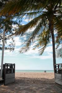 a beach with two palm trees and the ocean at Aimberê Eco Resort Hotel in Coqueiro