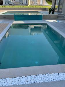 a swimming pool with blue water and white rocks at Twins Apartments in Plataniás