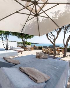 two beds with pillows sitting under an umbrella on the beach at Hotel Li Finistreddi in Cannigione