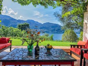 a table with a bottle of wine and flowers on a patio at Pitti Villa in Lierna