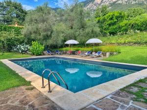a swimming pool with chairs and umbrellas in a yard at Pitti Villa in Lierna