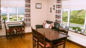 a dining room with a table and chairs and windows at Hilltop B & B in Kilkee