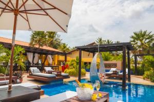 a resort pool with chairs and an umbrella at Aimberê Eco Resort Hotel in Coqueiro