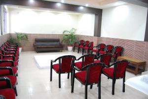 a waiting room with red chairs and a couch at Hotel Magnet House in Dehradun