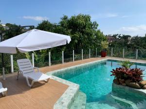 a swimming pool with a white umbrella and a white chair and an umbrella at House Flat Cacupé em Florianópolis in Florianópolis