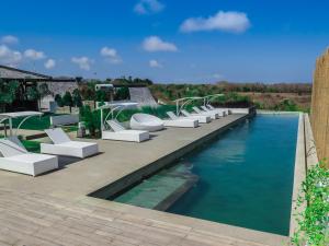 einen Pool mit weißen Liegestühlen und Wasser in der Unterkunft Rapture Surfcamps Green Bowl in Ungasan