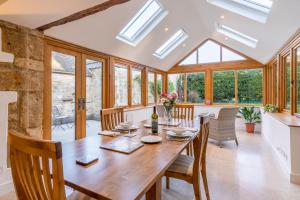 a dining room with a table and chairs and windows at Crofter's Barn in Chipping Norton