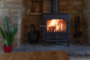 a wood stove with a fire in a room at Crofter's Barn in Chipping Norton