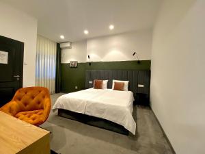 a bedroom with a bed and a chair at Victoria Rooms in Oradea