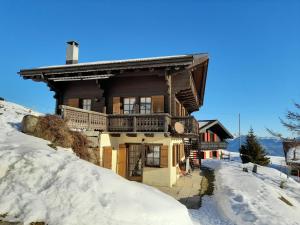 une maison en rondins dans la neige recouverte de neige dans l'établissement Chalet à la montagne, à Champoussin