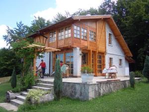 une grande maison en bois avec des personnes debout à l'extérieur dans l'établissement Villa Ema, à Sarajevo