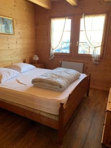 a bedroom with a large bed and two windows at Chalet à la montagne in Champoussin