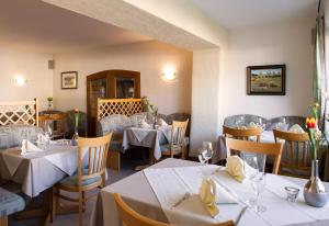 een restaurant met tafels en stoelen met witte tafelkleden bij Hotel Die Post Meerfeld in Meerfeld