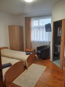 a hotel room with two beds and a chair and a window at Sveciu Namai Giles in Alytus
