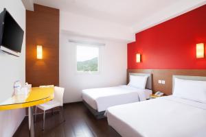 a hotel room with two beds and a desk at Amaris Hotel Gorontalo in Gorontalo