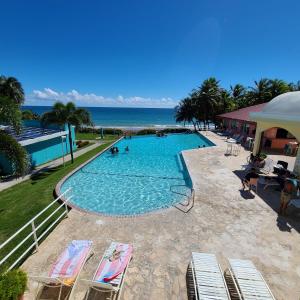 a swimming pool with chairs and the ocean in the background at Parador Maunacaribe - Maunabo in Maunabo
