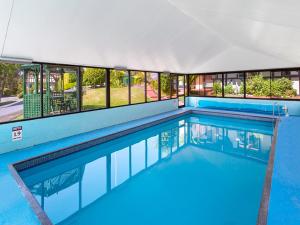 a swimming pool with blue water in a building at Village Family Motor Inn in Launceston