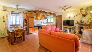 a living room with an orange couch and a kitchen at Villa La Cola Nerja by Ruralidays in Nerja