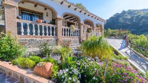 a garden in front of a house with flowers at Villa La Cola Nerja by Ruralidays in Nerja