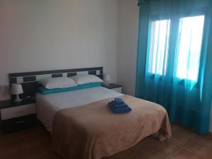 een slaapkamer met een bed en een raam met blauwe gordijnen bij Casa Vacanze Tiffany in Corralejo +42 foto's