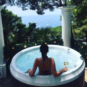 a woman sitting in a jacuzzi tub looking at the ocean at Villacore Luxury Guest House in Capri