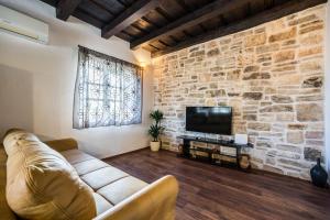 a living room with a couch and a stone wall at Holiday Home Sandra in Sukošan
