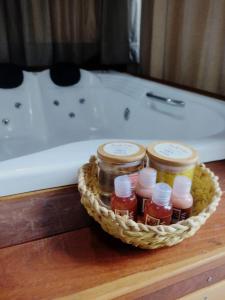 a basket of jars of jam in front of a bath tub at Pousada Santa Vila in Serra do Cipo