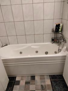 y baño con bañera blanca y pared de azulejos. en Apartament Lili, en Timisoara