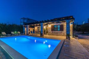 a villa with a swimming pool at night at Holiday Home Sandra in Sukošan