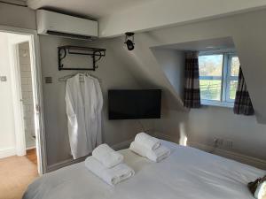 a bedroom with a white bed with towels on it at Rylands Farm Guest House in Wilmslow