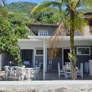 a house with chairs and tables and a palm tree at Casa pé na areia em Angra dos Reis in Angra dos Reis