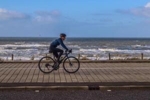 a woman riding a bike on a boardwalk near the ocean at Appartement Seabird in Zandvoort