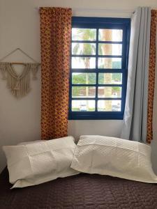 a bedroom with a bed and a window with curtains at Hospedaria Porto 27 in Porto Belo