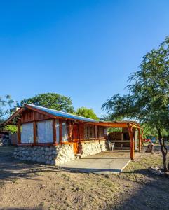 a log cabin with a porch and a tree at Aguada Escondida in San Marcos Sierras