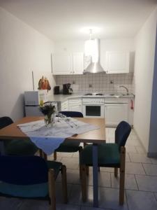 a kitchen with a table and chairs and a kitchen with white cabinets at Ferienwohnung am Bodensee- Preiswert in Überlingen