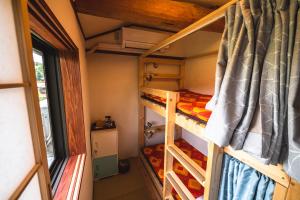 a bedroom with two bunk beds in a tiny house at 古民家ゲストハウスひまわり in Isa