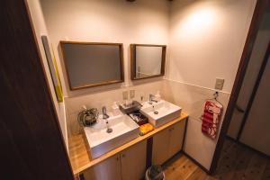 a bathroom with two sinks and two mirrors at 古民家ゲストハウスひまわり in Isa