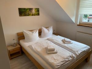 Schlafzimmer mit einem Bett mit weißer Bettwäsche und Kissen in der Unterkunft Hotel Garni und Gaststätte Zum Holzfäller in Schierke