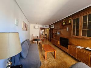 a living room with a blue couch and a table at Espacioso apartamento con impresionantes vistas y garaje privado - Dos Torres Tauriel in Zaragoza