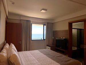 a hotel room with a bed and a television at Pituba Praiamar Hotel in Salvador