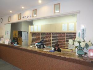 two people sitting at a counter in a restaurant at Natural Onsen Hostel Hidamari no Yu in Takayama