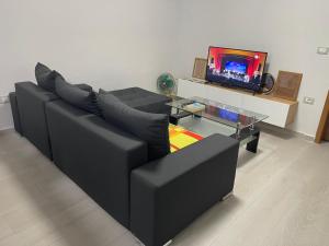 salon z czarną kanapą i telewizorem w obiekcie Apartament Gjergji w Sarandzie
